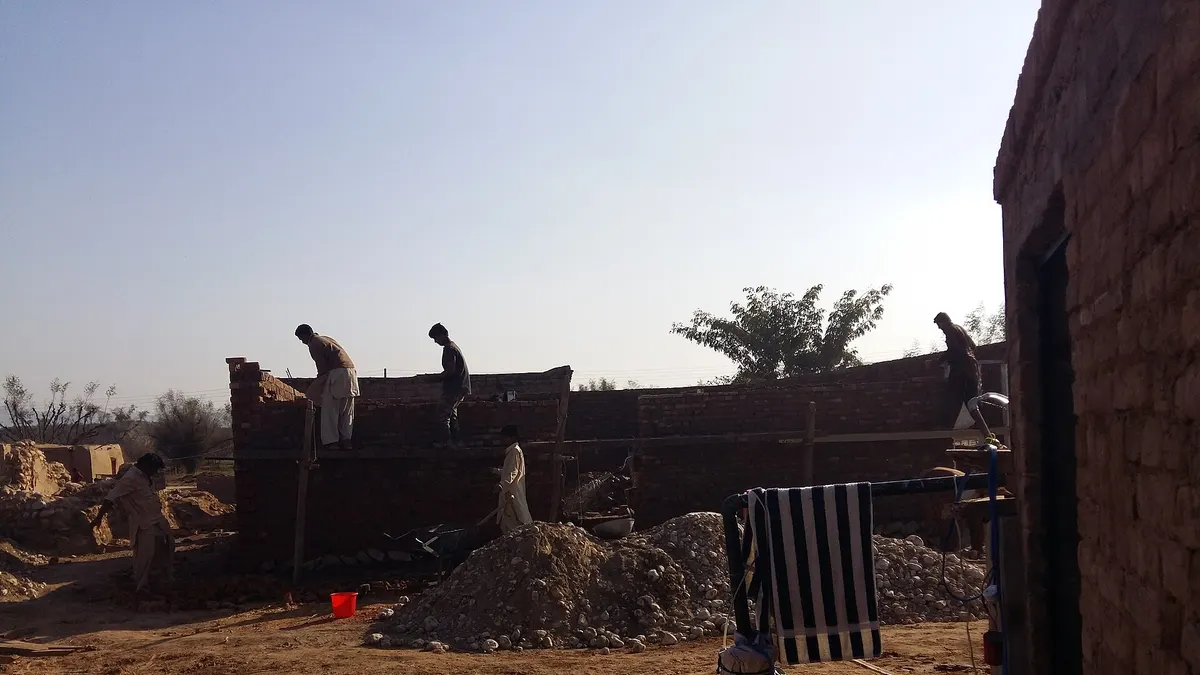 Workers laying brick walls of a house under construction in Pakistan