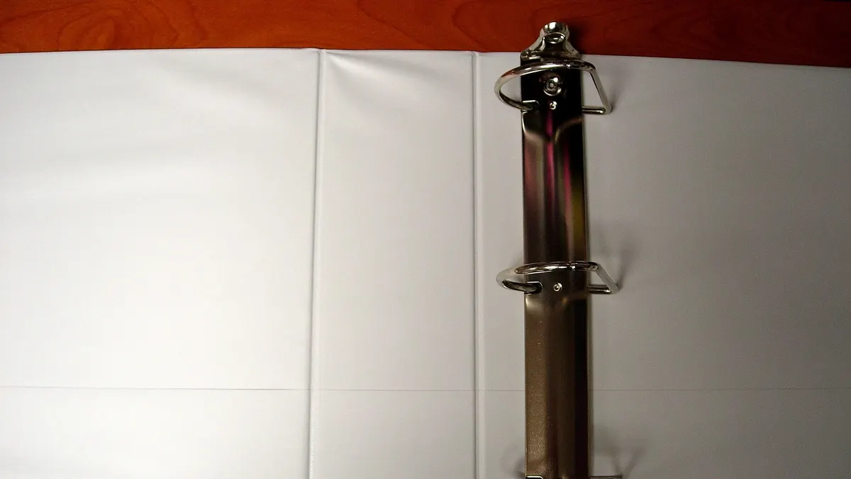 An empty open ring binder lying on a wooden desk