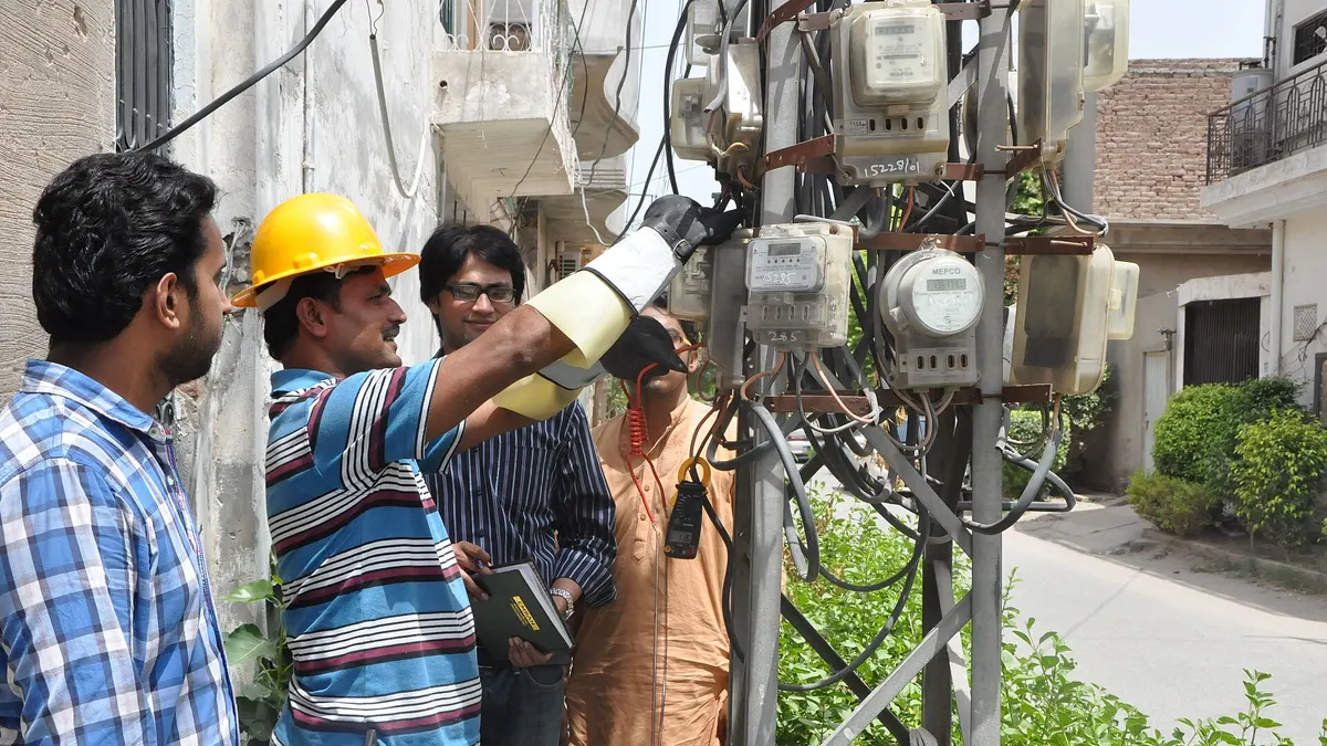 A MEPCO team checking a cluster of household electricity meters on a pole in southern Punjab