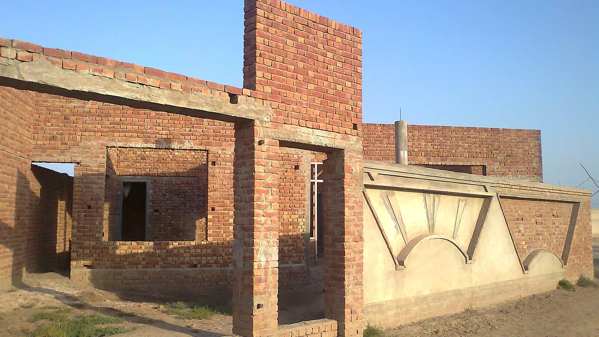 The brick grey structure of a single-storey house in Makhdoom Rashid, Punjab, before plaster