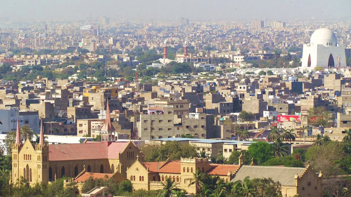 Flat concrete rooftops across central Karachi, with Mazar-e-Quaid in the distance