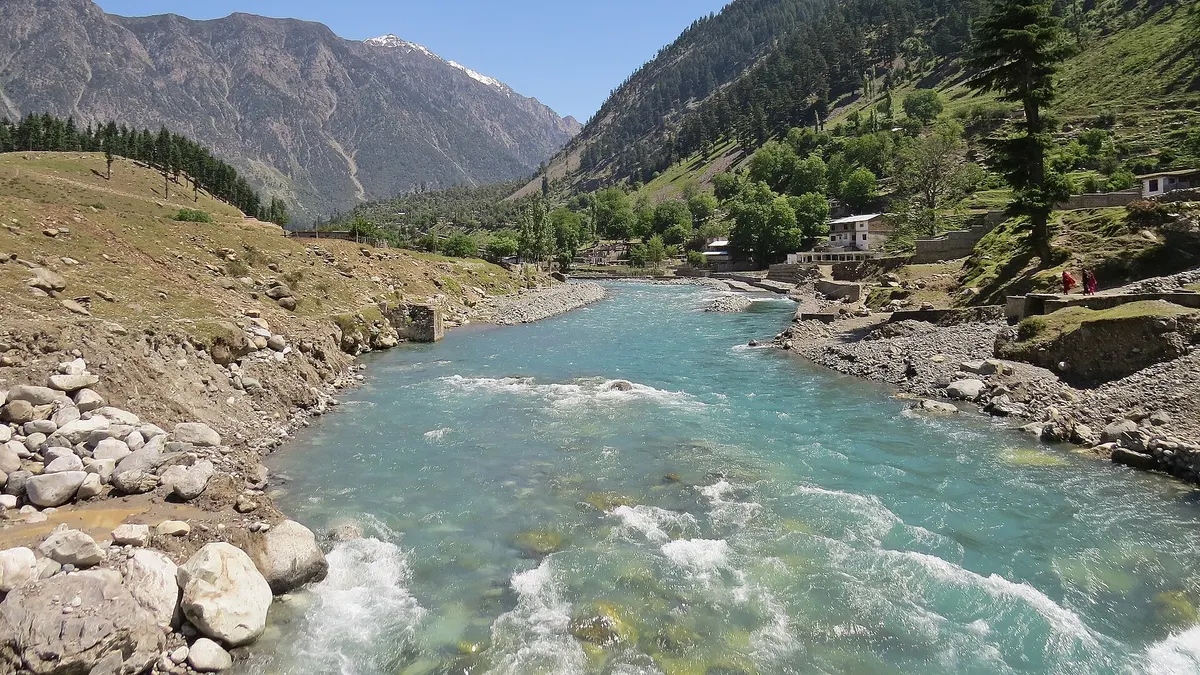 The Swat River at Kalam, with pine-covered slopes and a snow-capped peak behind